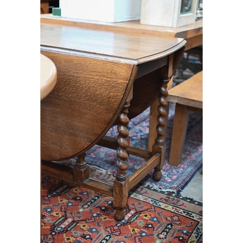 216 - An early 20th century oak drop-leaf dining table on gateleg action with barley twist supports