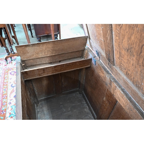 296 - A large 18th century panelled oak coffer with later carved front, the hinged top enclosing storage a... 