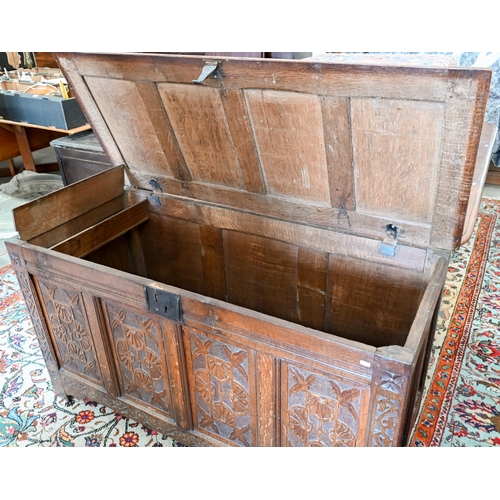 296 - A large 18th century panelled oak coffer with later carved front, the hinged top enclosing storage a... 