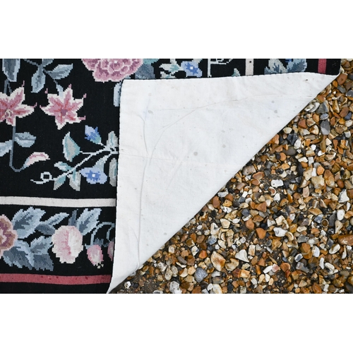 510 - A traditional needlepoint rug, floral design on black ground, 183 x 123 cm