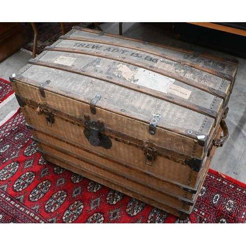 533 - A 1920s dome top canvas covered trunk with travel labels and stenciled ownership, wooden bands, bras... 