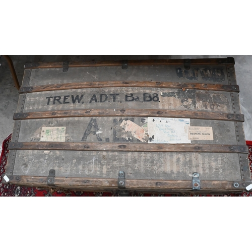 533 - A 1920s dome top canvas covered trunk with travel labels and stenciled ownership, wooden bands, bras... 