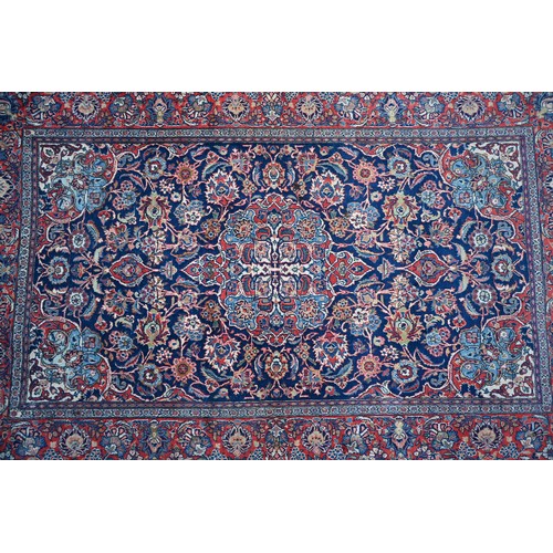 150 - A Persian Kashan rug, palmettes and rosettes arranged symmetrically around the large central floral ... 