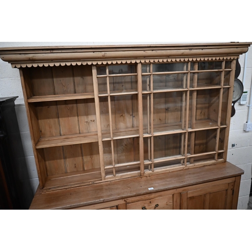 464 - An antique waxed pine kitchen dresser, the raised back fitted with pair of astragal glazed sliding d... 