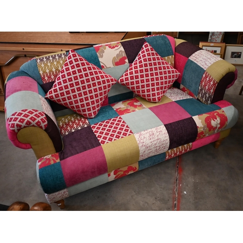 489 - A modern two seater sofa with straight back and scroll arms, with bright patchwork fabric upholstery... 