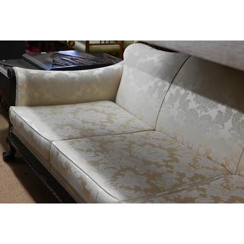 491 - A carved mahogany wing-armed sofa, in old gold damask upholstery, three ball and claw front supports... 