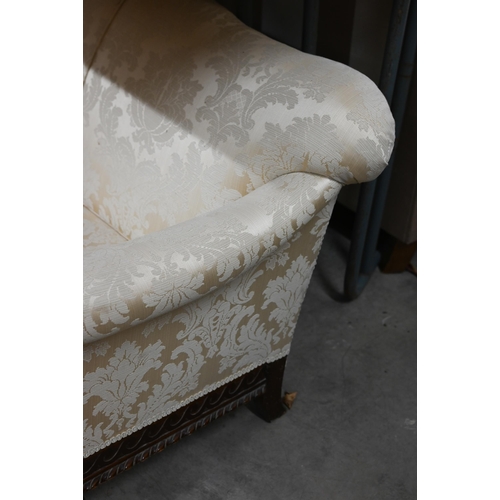 491 - A carved mahogany wing-armed sofa, in old gold damask upholstery, three ball and claw front supports... 