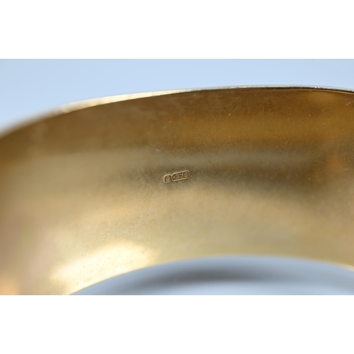 216 - A 9ct yellow gold oval half-hinged wide bangle with chased foliate decoration (missing safety chain)... 