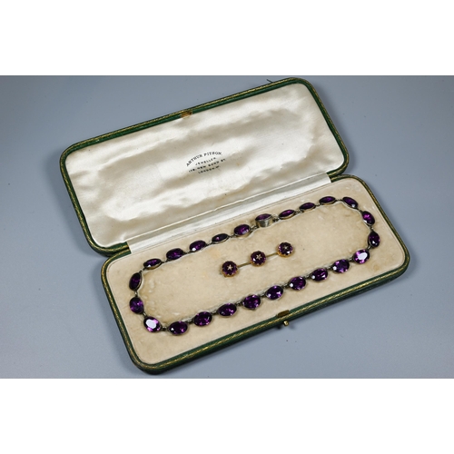 223 - A Victorian rivière necklace, formed of twenty four foil-backed oval faceted purple pastes in gilt m... 