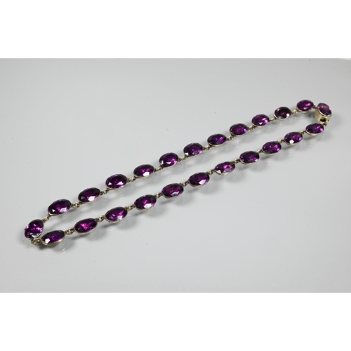 223 - A Victorian rivière necklace, formed of twenty four foil-backed oval faceted purple pastes in gilt m... 