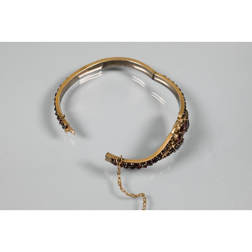 252 - A Victorian half-hinged bangle set overall with garnets (possibly), silver-gilt, in as found conditi... 