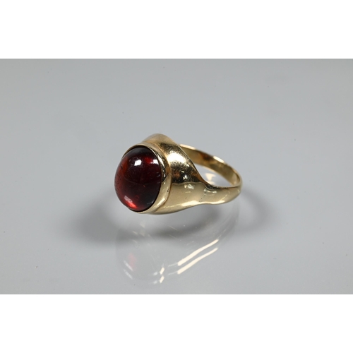 254 - A cabochon garnet set ring in yellow metal setting of plain form, size P, unmarked and untested