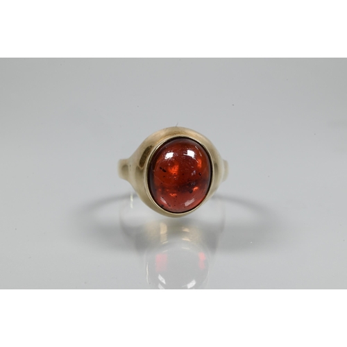 254 - A cabochon garnet set ring in yellow metal setting of plain form, size P, unmarked and untested