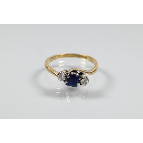 257 - A sapphire and diamond three stone ring in crossover setting, the square blue sapphire flanked by a ... 