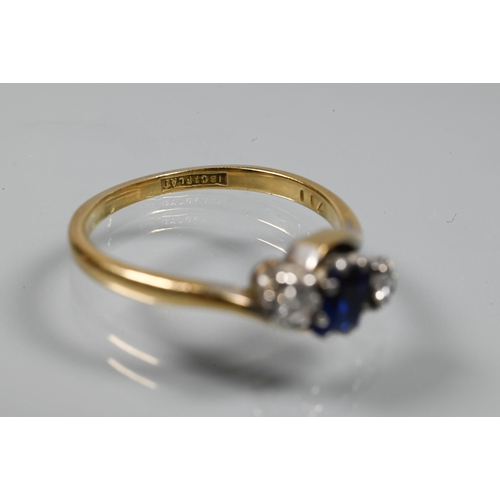 257 - A sapphire and diamond three stone ring in crossover setting, the square blue sapphire flanked by a ... 