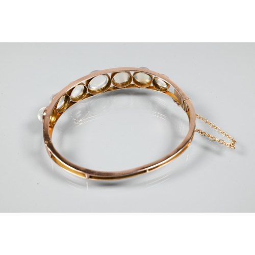 264 - A Victorian oval half-hinged bangle of open wirework form, set with seven graduated circular cabocho... 