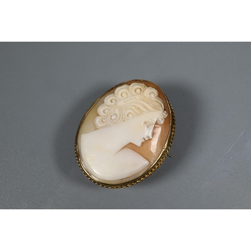 269 - An oval shell cameo brooch featuring lady with elaborate hairstyle, in yellow metal rope edge mount ... 