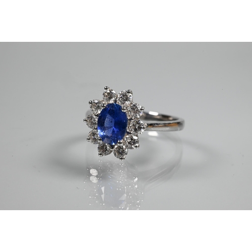 277 - An oval cluster ring, the central oval tanzanite (possibly) surrounded by ten claw set diamonds, sta... 