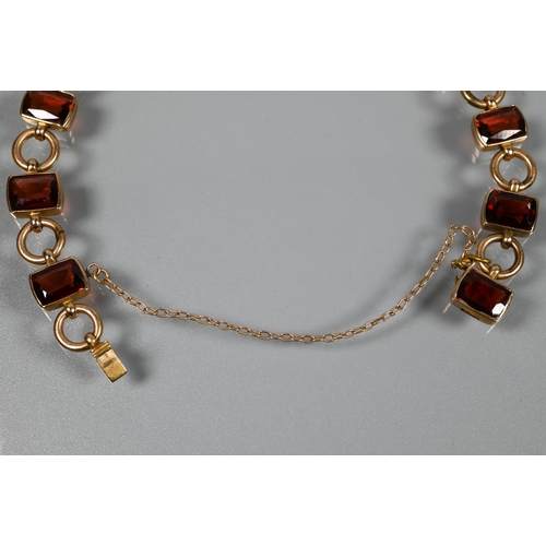 290 - A garnet set bracelet, the rectangular garnet set links interspersed with circular chain links, conc... 