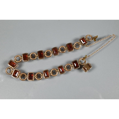 290 - A garnet set bracelet, the rectangular garnet set links interspersed with circular chain links, conc... 