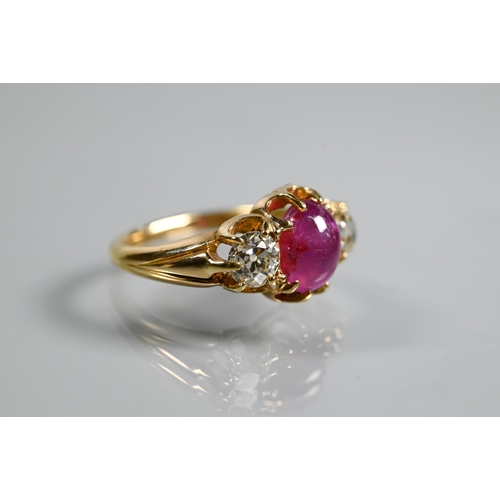 311 - A three stone ring, the central oval cabochon ruby with circular diamond to each side, claw set, unm... 