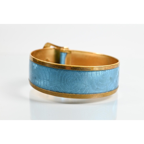 321 - A gilt metal and turquoise enamel bangle in the form of a buckle with stylised 'spider web' enamel d... 