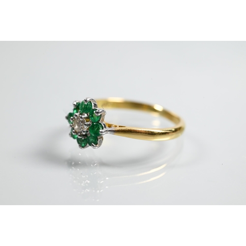 322 - An emerald and diamond daisy ring, the central diamond surrounded by eight small emeralds, yellow an... 