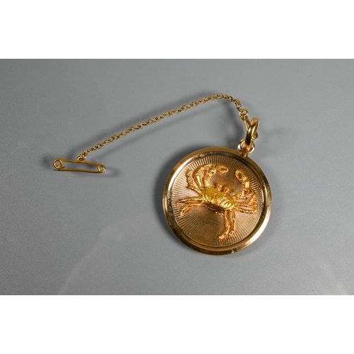 323 - A circular yellow metal pendant disc featuring a naturalistically detailed crab in relief on engine ... 