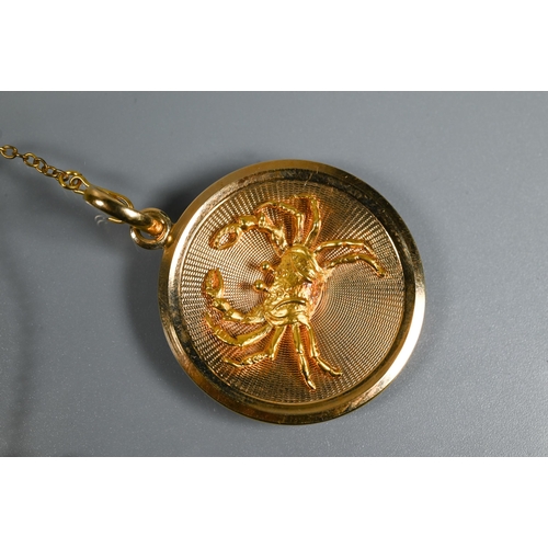 323 - A circular yellow metal pendant disc featuring a naturalistically detailed crab in relief on engine ... 