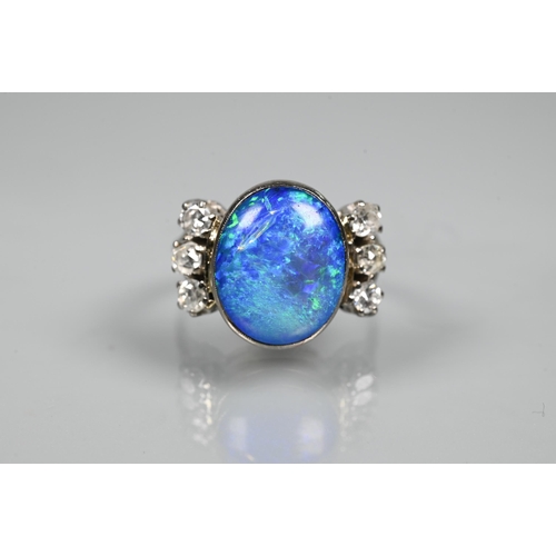 352 - An opal and diamond ring, the large opal of blue iridescence with three diamonds to each side, white... 