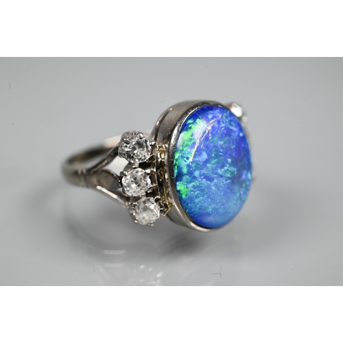 352 - An opal and diamond ring, the large opal of blue iridescence with three diamonds to each side, white... 