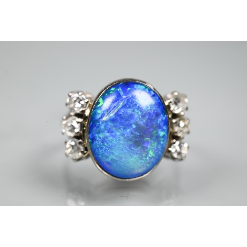 352 - An opal and diamond ring, the large opal of blue iridescence with three diamonds to each side, white... 