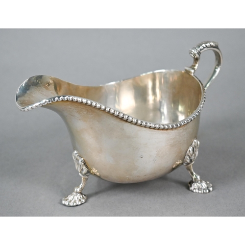 44 - Silver sauce boat in the Georgian manner, with beaded rim and scroll handle, on three shell feet, Wa... 