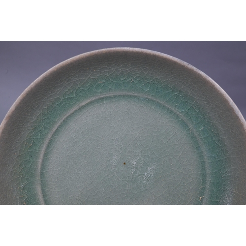 465 - A Chinese celadon dish with combed exterior, covered in a crackled olive green glaze thinning in col... 