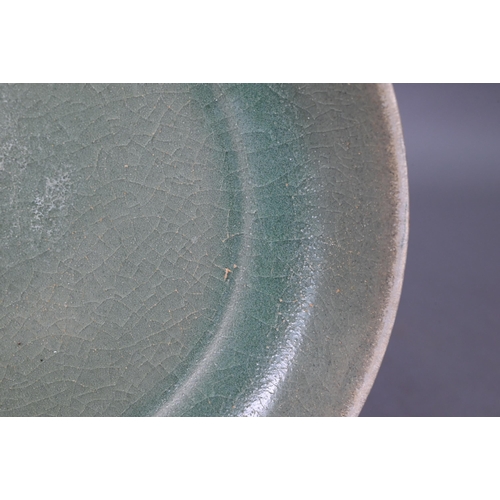 465 - A Chinese celadon dish with combed exterior, covered in a crackled olive green glaze thinning in col... 