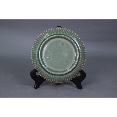 465 - A Chinese celadon dish with combed exterior, covered in a crackled olive green glaze thinning in col... 