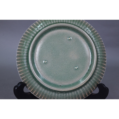 465 - A Chinese celadon dish with combed exterior, covered in a crackled olive green glaze thinning in col... 