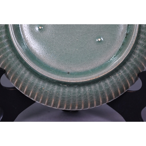 465 - A Chinese celadon dish with combed exterior, covered in a crackled olive green glaze thinning in col... 