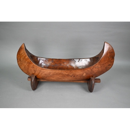 491 - An Indonesian stained and hollowed hardwood fruit bowl on stand in the form of a dugout canoe, 65 cm... 