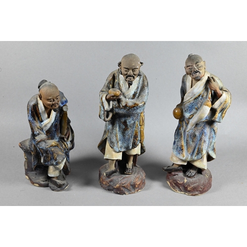 496 - Three early 20th century Chinese Shiwan bique porcelain part-glazed figures of elders holding variou... 