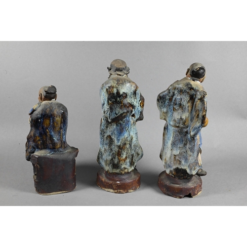 496 - Three early 20th century Chinese Shiwan bique porcelain part-glazed figures of elders holding variou... 