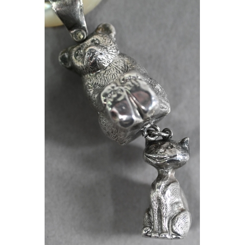 55 - An Edwardian silver baby's rattle with mother of pearl teething ring, hung with teddy bear and grinn... 