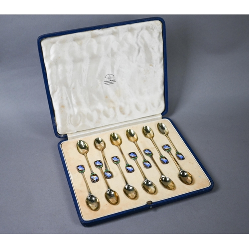 68 - Cased set of twelve Art Deco silver gilt coffee spoons with finials pierced and enamelled with butte... 