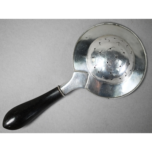 9 - Danish unmarked white metal tea strainer with beaded rim and ebonised carved handle, 17cm long
