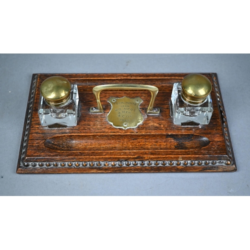 1316 - A brass mounted oak ink stand, with two glass bottles and centred by an engraved shield 'Compliments... 