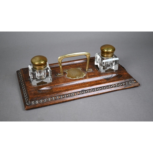 1316 - A brass mounted oak ink stand, with two glass bottles and centred by an engraved shield 'Compliments... 