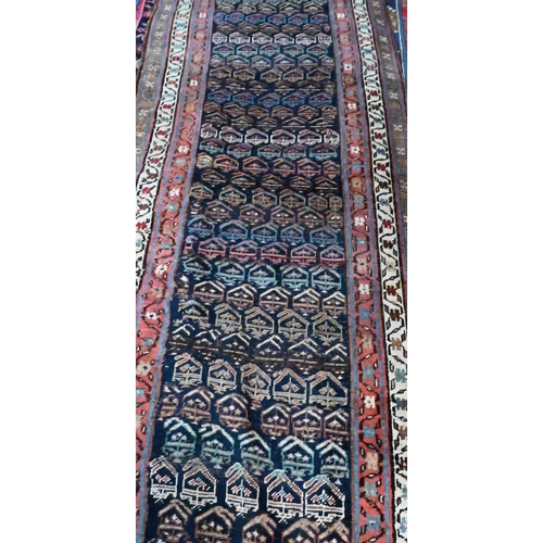 812 - An antique Persian Kurd runner, the ink blue ground with repeating rows of stylised boteh, 417 cm&nb... 