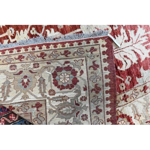 820 - A contemporary Indian Agra carpet, the red-pink ground with stylised floral design, 323 cm x 242 cm