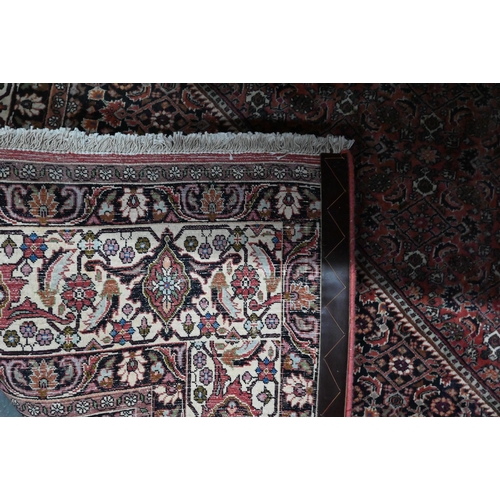 824 - A Persian Bidjar red ground carpet, centred by a diamond floral lozenge, 335 cm x 247 cm