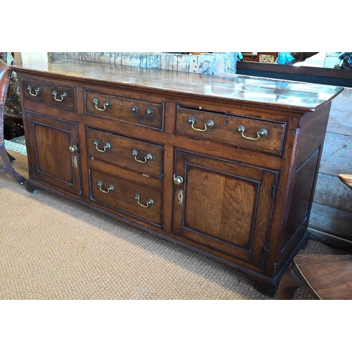 854 - An 18th century oak low dresser, the three plank top over an arrangement of five drawers and two cup... 